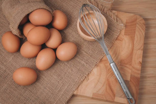 istock Kitchen metal wire and raw eggs on the wooden board 639663276