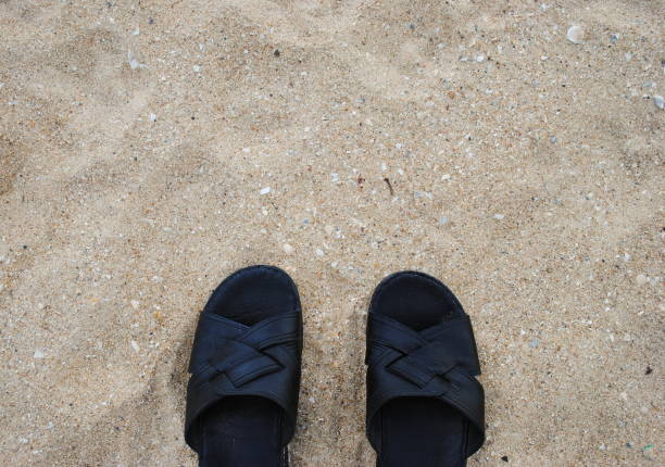 istock Black slippers on a background of sand 639664970