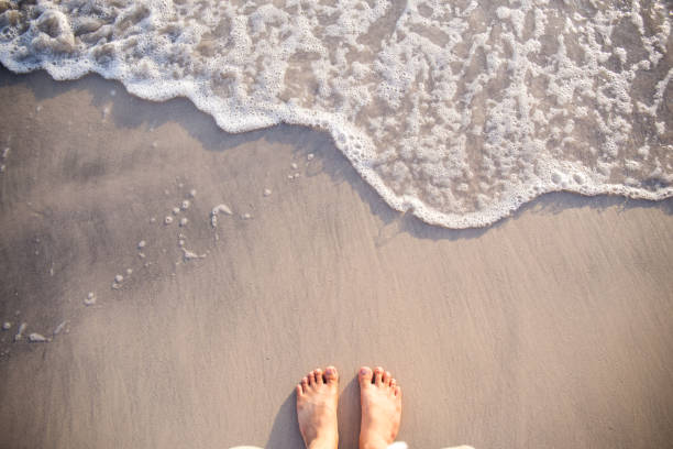 istock feet on sea sand and wave 639665078