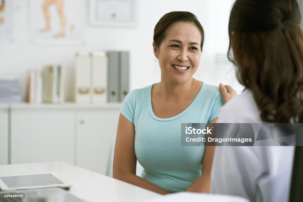 At doctor Doctor reassuring Vietnamese woman Patient Stock Photo