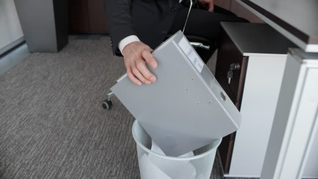 SLO MO DS Businessman throwing a ring binder into the trash