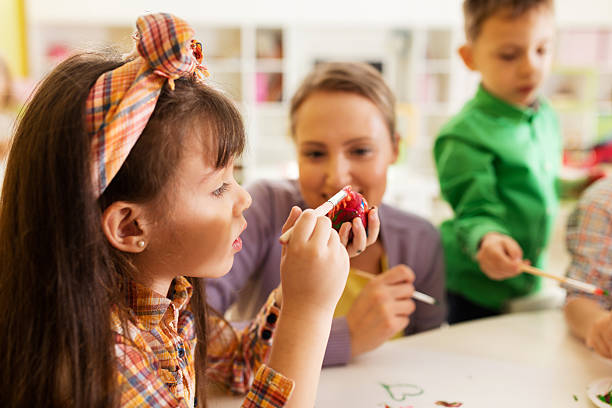 istock Creative small girl coloring Easter egg with paintbrush. 639681028