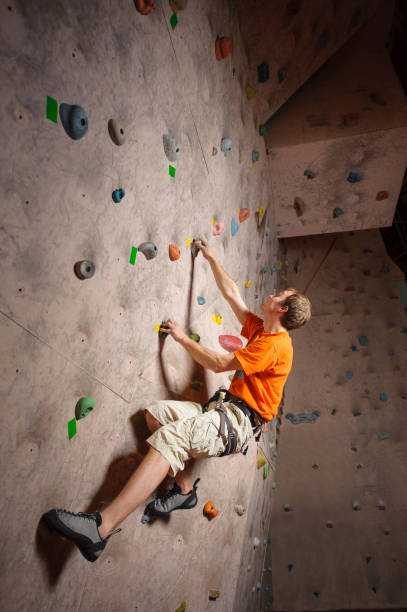 istock Male climber practicing rock-climbing on a rock wall indoors 639682146