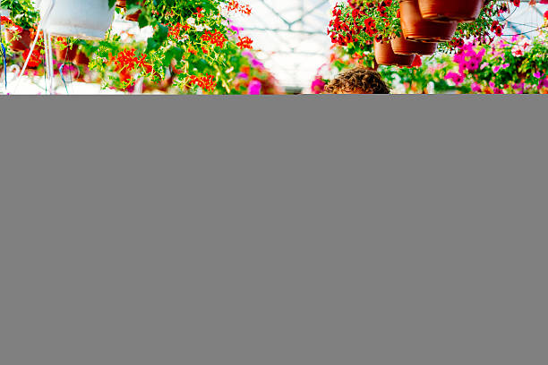 Portrait of handsome entrepreneur in plant nursery, proudly standing in front of her new small business and showing blackboard and smiling. Empty black board is suitable for text and editing.