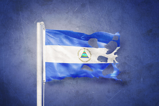 Bandera rasgada de Nicaragua ondeando contra el fondo grunge photo