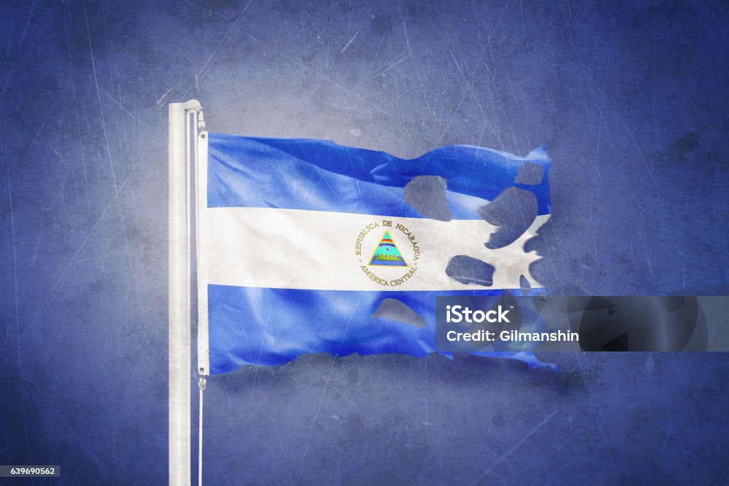 Torn flag of Nicaragua flying against grunge background Torn flag of Nicaragua flying against grunge background. Backgrounds Stock Photo