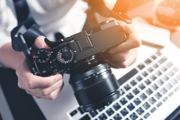 Photographer workplace Photographer holding camera on desk ready to  editing photos on laptop. Studio work, photo service concept. Workplace photography stock pictures, royalty-free photos & images