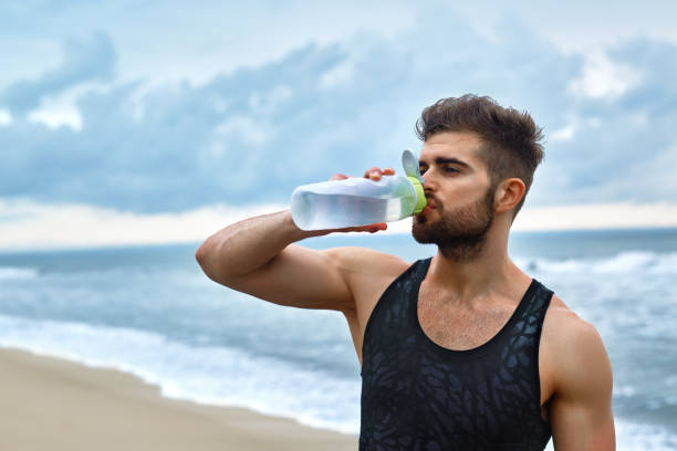 istock Man Drinking Refreshing Water After Workout At Beach. Drink 639697102
