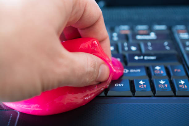 Keyboard cleaning gel in work. Keyboard cleaning gel in work. Hand and pink gel. putty stock pictures, royalty-free photos & images