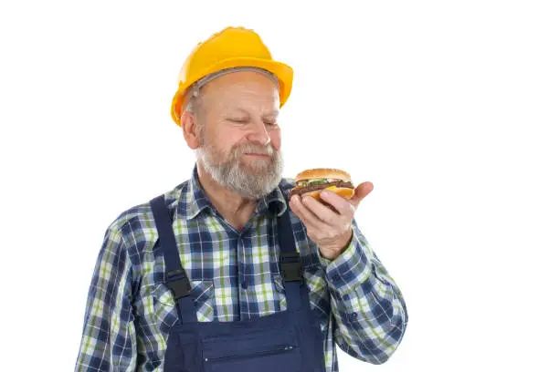 Picture of a hungry mechanic having a lunch break, eating hamburger