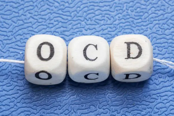 Word ocd (obsessive compulsive disorder) on a wooden cubes on a blue background
