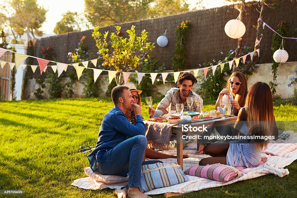 Grupo de amigos curtindo piquenique ao ar livre no jardim - Foto de stock de Piquenique royalty-free