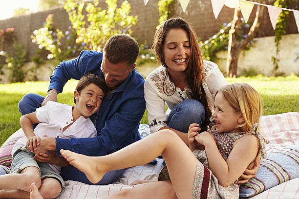 parents jouant au jeu avec des enfants sur une couverture dans le jardin - tickling little girls child sister photos et images de collection