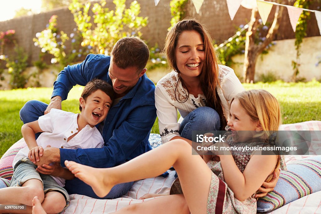 Parents Playing Game With Children On Blanket In Garden Vacation Rental Stock Photo
