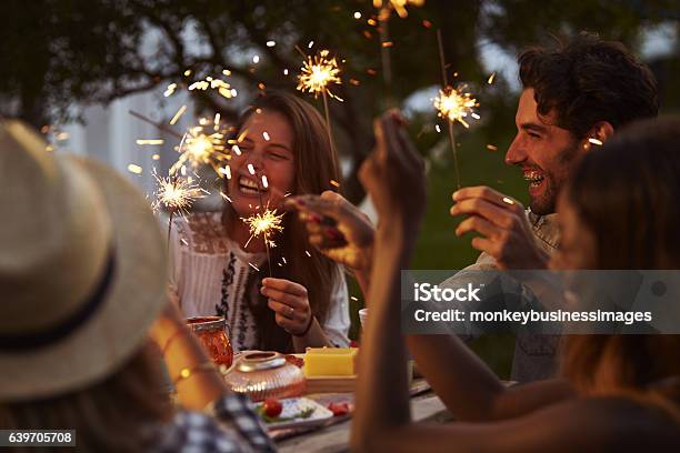 Friends With Sparklers Eating Food And Enjoying Party Stock Photo - Download Image Now