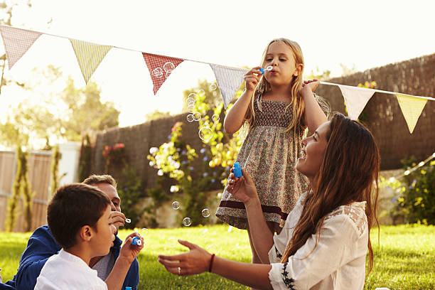 les parents soufflent des bulles avec des enfants dans le jardin - bubble wand outdoors little boys mother photos et images de collection