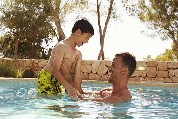 Father And Son On Vacation Having Fun In Outdoor Pool