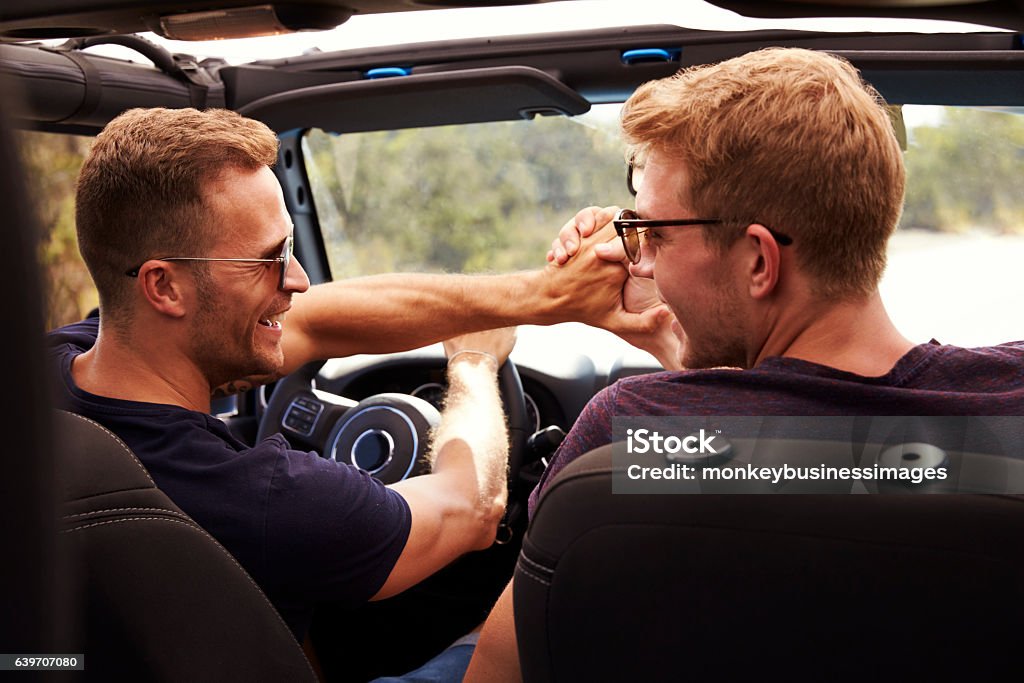 Two Male Friends Driving Open Top Car On Country Road Car Stock Photo