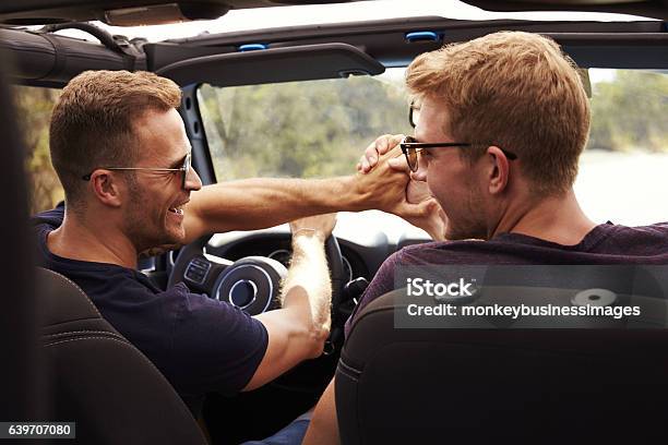 Two Male Friends Driving Open Top Car On Country Road Stock Photo - Download Image Now