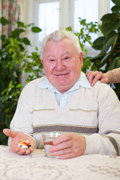 istock Elderly man holding pills and water 639707152
