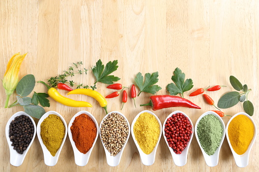 Aromatic and colorful spices in ceramic containers on a wooden background.