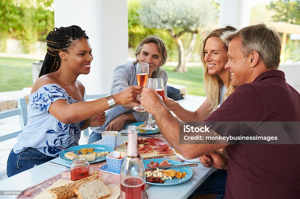 Four friends making a toast at a dinner table on a patio 30-39 Years Stock Photo