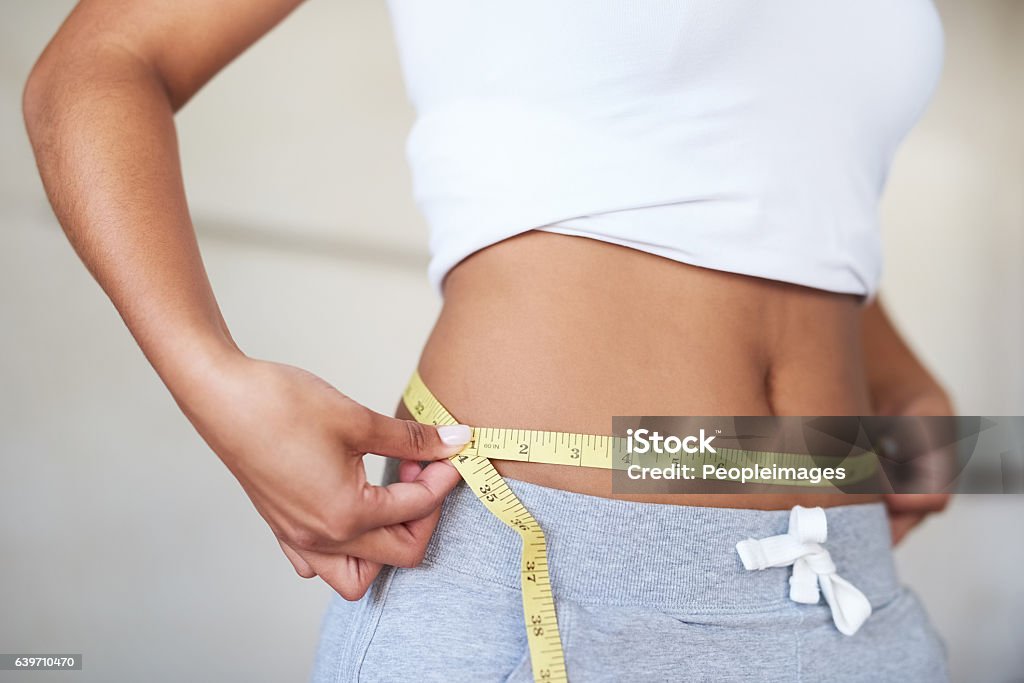 You can get the same results Cropped shot of a young woman measuring her waist in the bathroom Dieting Stock Photo