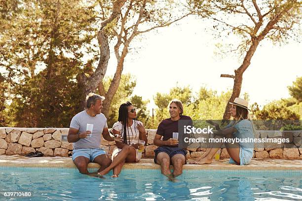 Two Couples Sit At Poolside Talking Front View Stock Photo - Download Image Now - Swimming Pool, Friendship, Vacation Rental