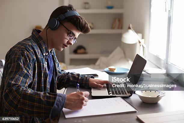 Foto de Adolescente Usando Fones De Ouvido Trabalha Em Mesa Em Seu Quarto e mais fotos de stock de Adolescente