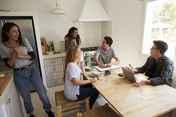 istock Teens hanging out in kitchen, doing homework and making food 639710674