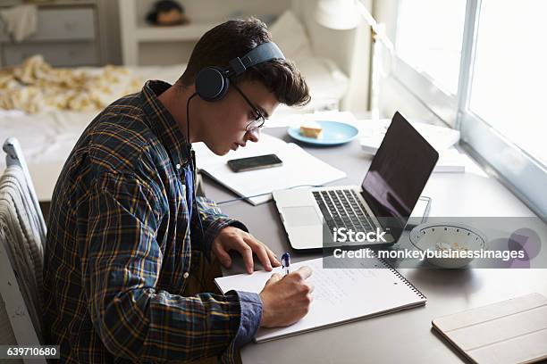 Adolescente Con Auriculares Trabaja En El Escritorio De Su Dormitorio Foto de stock y más banco de imágenes de Adolescente