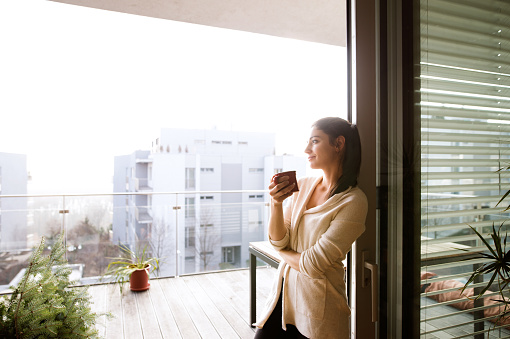 Mujer relajándose en el balcón sosteniendo una taza de café o té photo