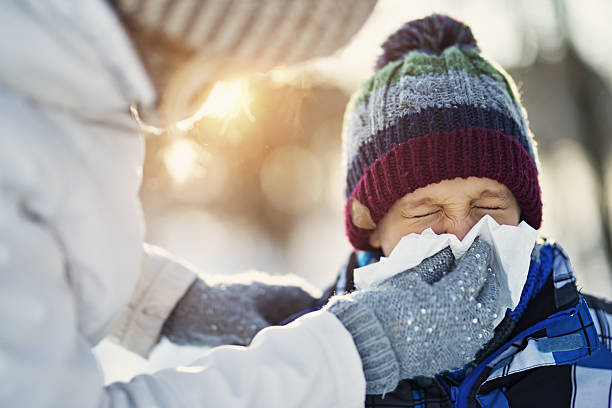 мать сморкаться с больным сыном во время зимней прогулки - cold and flu flu virus sneezing illness стоковые фото и изображения