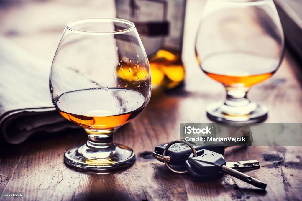 Cup of cognac whiskey or brandy and the keys car. Alcoholism. Cup cognac or brandy hand man the keys to the car and irresponsible driver. Drunk Driving Stock Photo