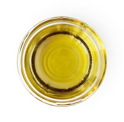 Closeup of olive oil in gravy boat or glass sauce server, top view isolated on white