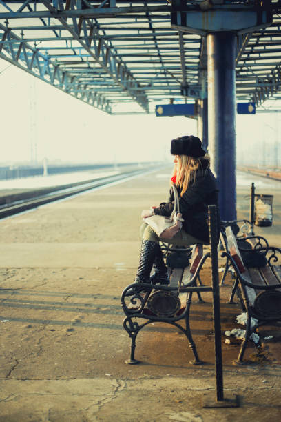 nachdenkliche junge frau mit langen blonden haaren warten zug - leaving loneliness women railroad track stock-fotos und bilder