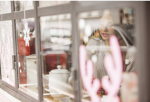Blurred view trough the window at single girl while she is sitting in coffee shop and waiting for friends
