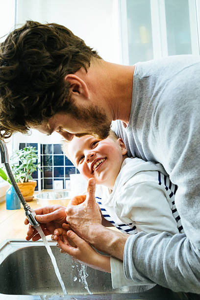 istock Father Washing Sons Hands In Kitchen Sink After Cooking Together 639716366