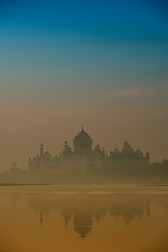 Colored background for themes about India - Silhouette of word famous Taj Mahal in Agra, India - seen from an usual standpoint at the banks of Yamua River.