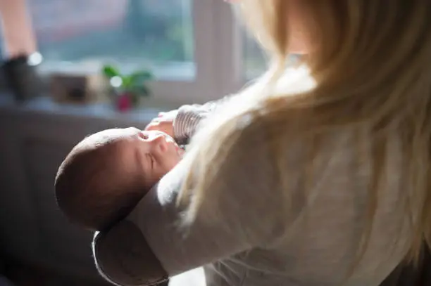 Photo of Unrecognizable young mother holding baby son in her arms