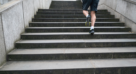 Close-up on feet of a man running outdoors climbing up the stairs - healthy lifestyle concepts
