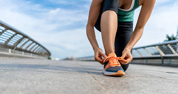istock Woman running outdoors and tying her shoelace 639729092