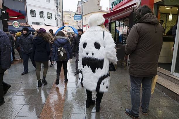 Istanbul, Turkey - January 15, 2017: A couple are walking at The Istanbul, Kadikoy shopping street. The woman is wearing a fur coat. There is a funny pattern on the coat looks like a funny ghost face. There are Turkish People and shops at the street too.