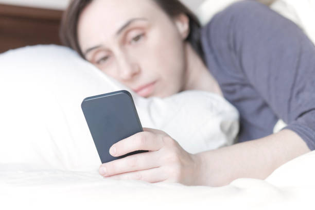 istock Woman Lying on Bed Checking Her Phone 639740520