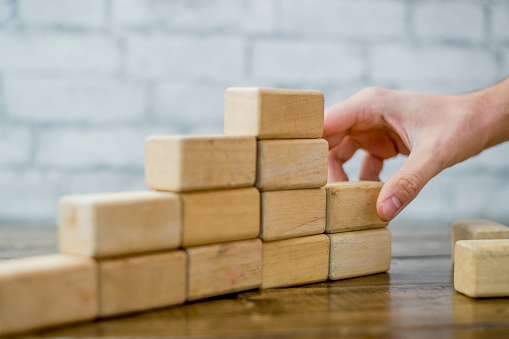 An anonymous hand adds blocks to a 3D graph of business growth.