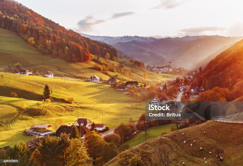 Scenic panoramic view of a picturesque mountain valley in autumn Scenic panoramic view of a picturesque mountain valley in autumn at sunset. Colourful countryside landscape with mountain forests, traditional houses and old monastery. Germany, Black Forest. Black Forest - Germany Stock Photo