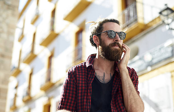 Bearded young man in sunglasses using phone, Ibiza, Spain