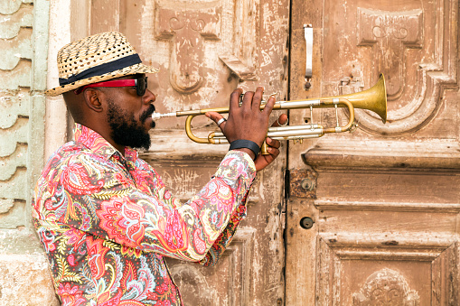 Cuban musician playing trumpet standing in front of the old door in Havana, Cuba