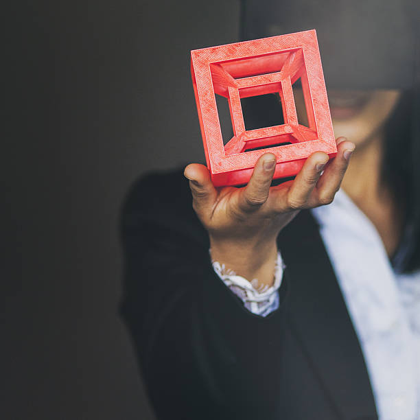 Woman holding a 3d printed cube Businesswoman wearing virtual reality goggles and holding a bright red 3d printed model of a hypercube 3d printing hand stock pictures, royalty-free photos & images