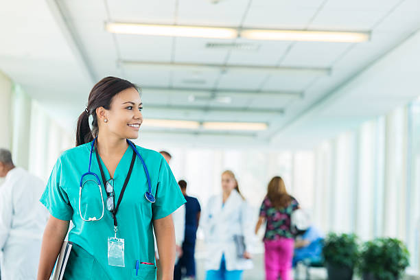 alegre enfermera hispana camina por el pasillo del hospital - happiness student cheerful lifestyle fotografías e imágenes de stock